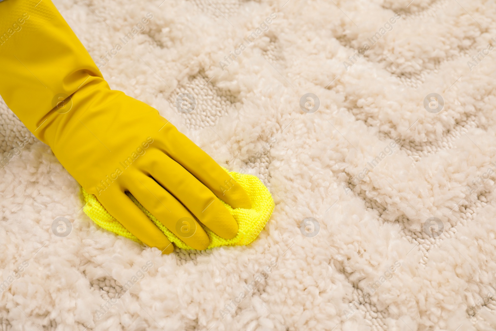 Photo of Woman in rubber gloves cleaning carpet with rag, closeup. Space for text