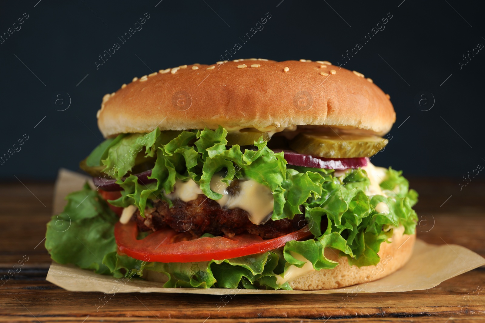 Photo of Delicious burger with beef patty and lettuce on wooden table, closeup