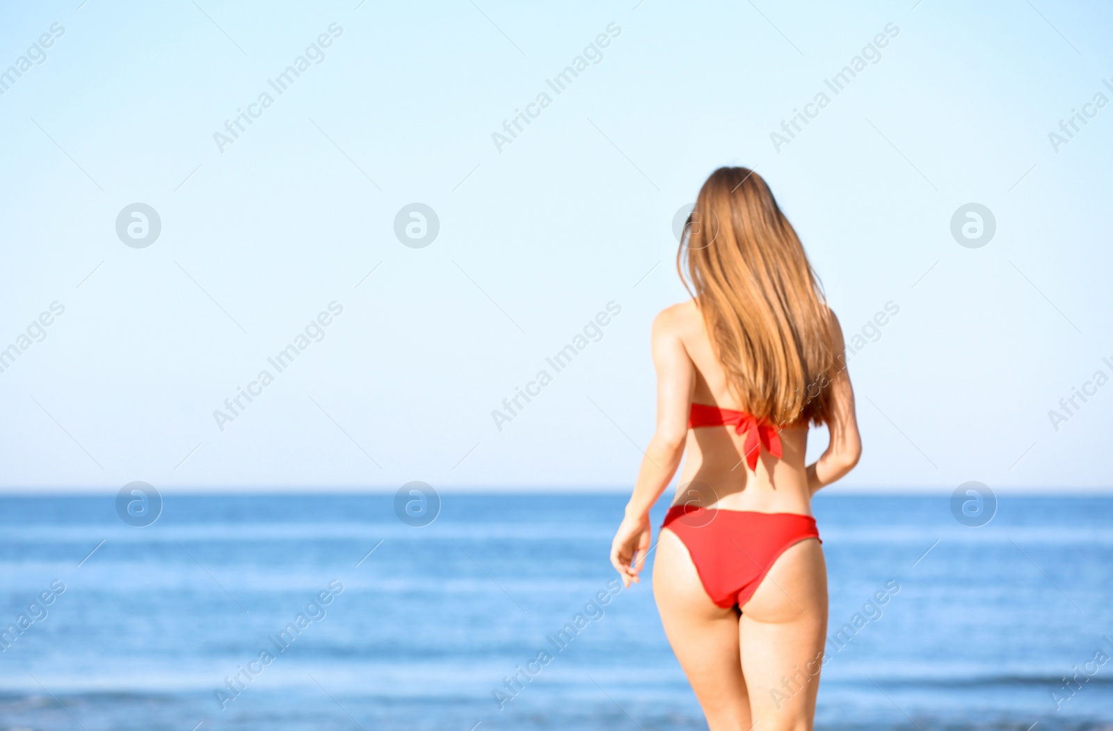 Photo of Young woman in red bikini near sea. Space for text