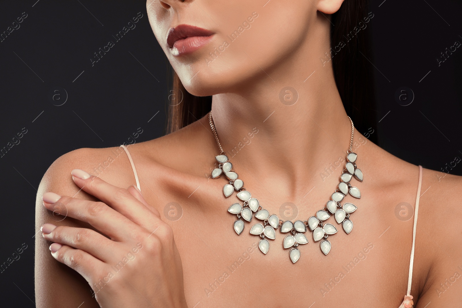 Photo of Beautiful young woman with elegant jewelry on dark background, closeup