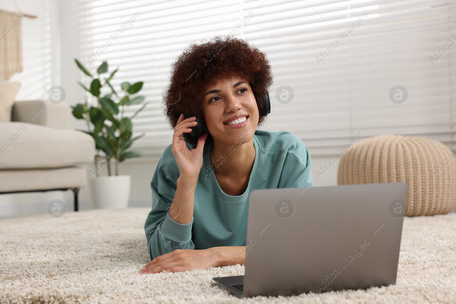 Photo of Beautiful young woman in headphones using laptop in room