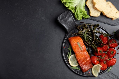 Delicious cooked salmon and vegetables served on black table, flat lay with space for text. Healthy meals from air fryer