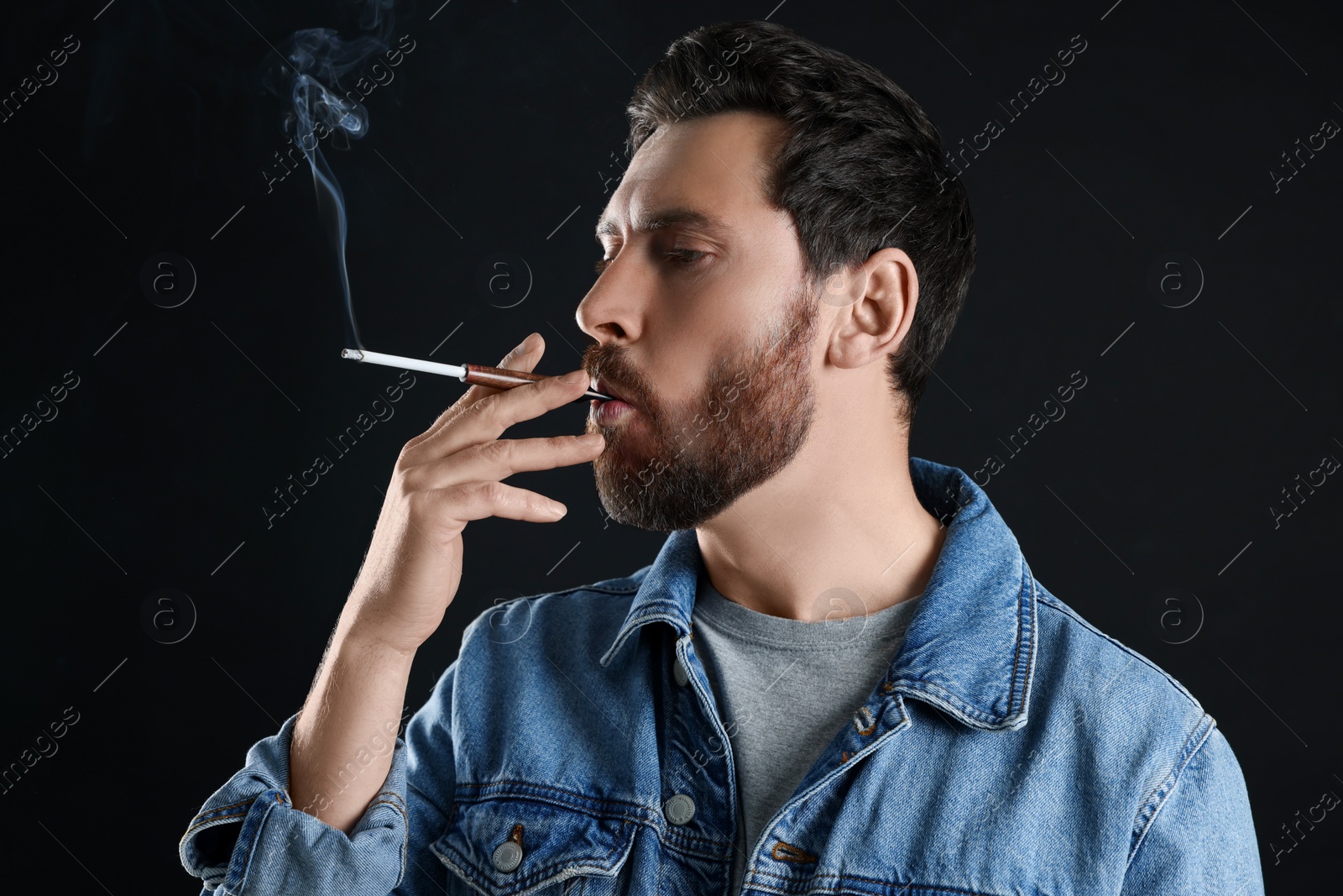 Photo of Man using cigarette holder for smoking on black background