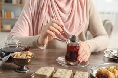 Woman with cup of delicious Turkish tea at wooden table, closeup