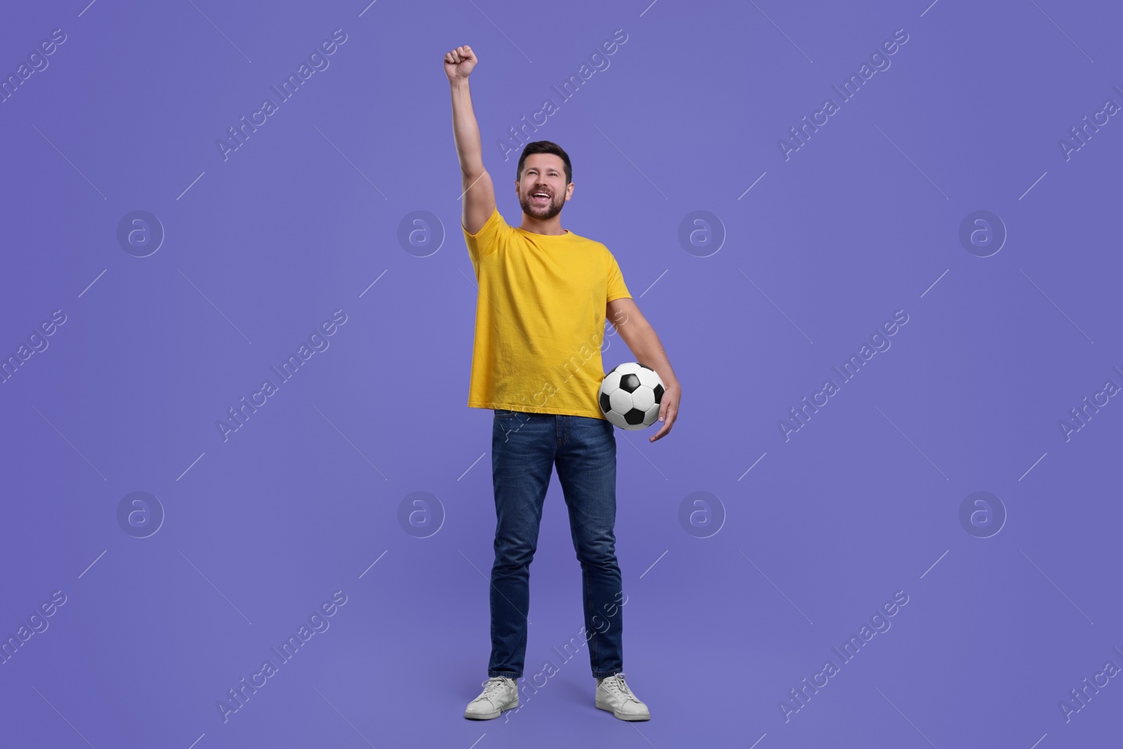 Photo of Emotional sports fan with ball celebrating on purple background