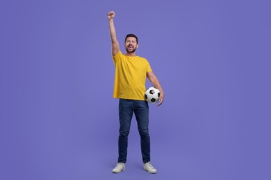 Emotional sports fan with ball celebrating on purple background