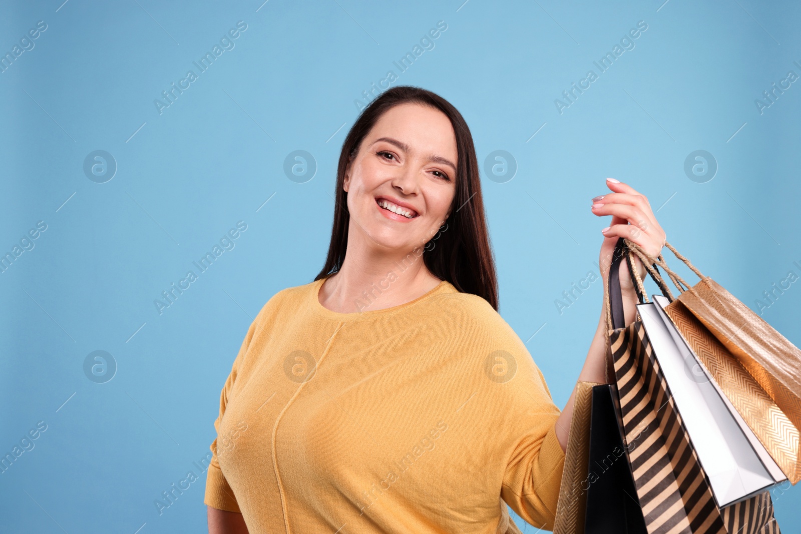 Photo of Beautiful overweight woman with shopping bags on turquoise background