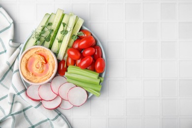 Plate with delicious hummus and fresh vegetables on white table, flat lay. Space for text