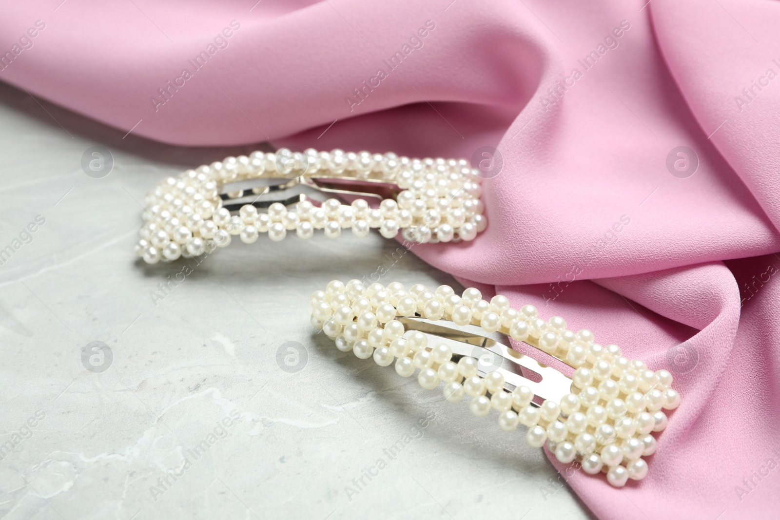 Photo of Stylish hair clips and fabric on grey marble table