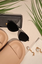 Flat lay composition with stylish sunglasses and black leather case on sand