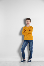Photo of Cute little boy posing near light wall