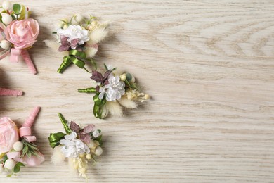 Photo of Stylish boutonnieres on white wooden table, flat lay. Space for text