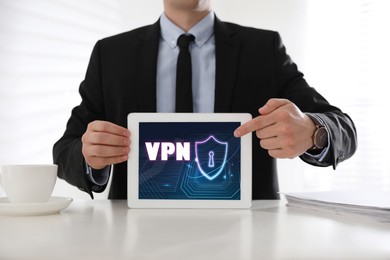 Image of Man holding modern tablet with switched on VPN indoors, close up