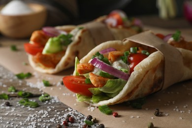 Photo of Delicious pita wrap with meat and vegetables on wooden table. closeup