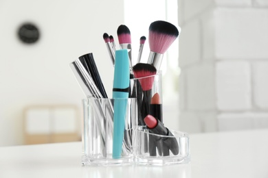 Photo of Organizer with cosmetic products for makeup on table indoors