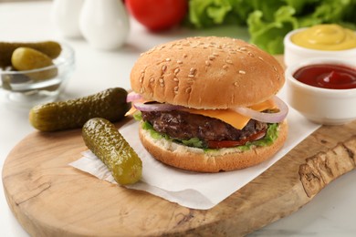 Photo of Tasty hamburger with patty, cheese and vegetables served on white table