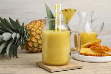 Photo of Tasty pineapple smoothie and fruit on wooden table