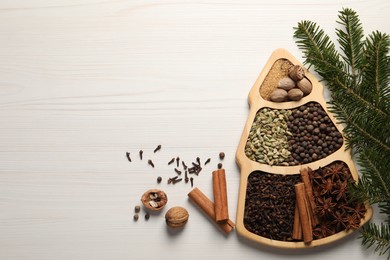 Different spices, nuts and fir branches on white wooden table, flat lay. Space for text