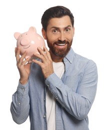 Happy man with ceramic piggy bank on white background