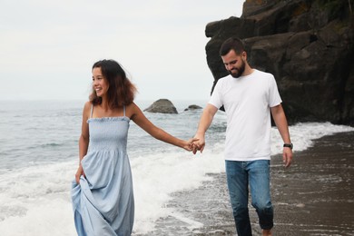 Photo of Happy young couple walking on beach near sea