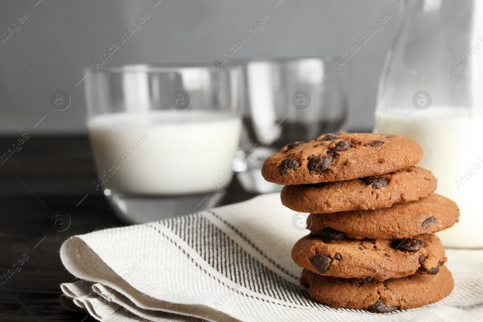 Photo of Stack of tasty chocolate chip cookies and milk on table