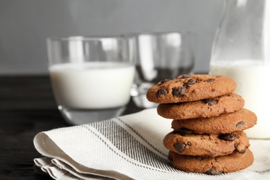 Photo of Stack of tasty chocolate chip cookies and milk on table