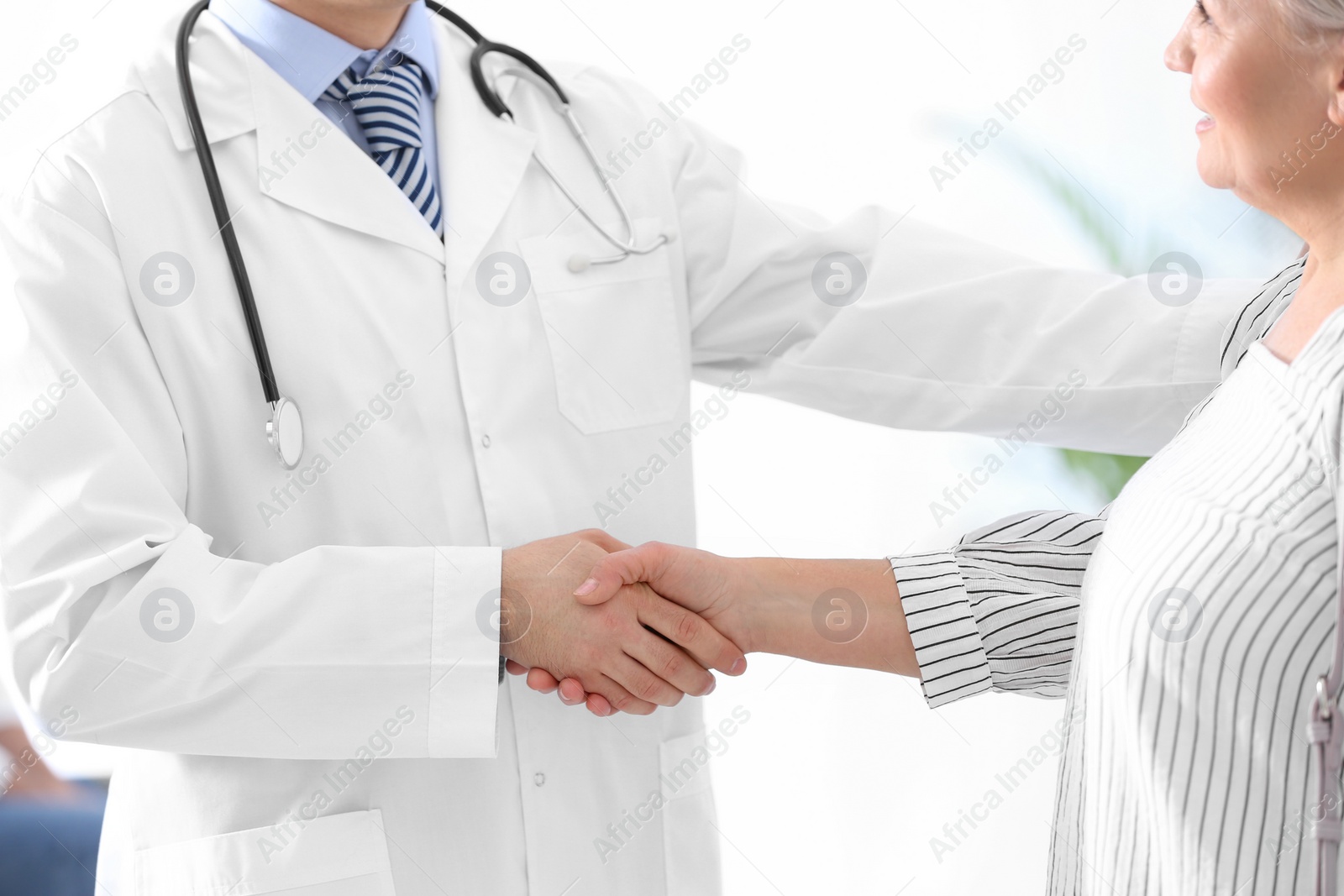 Photo of Doctor and patient shaking hands in hospital, closeup