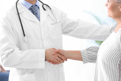 Doctor and patient shaking hands in hospital, closeup