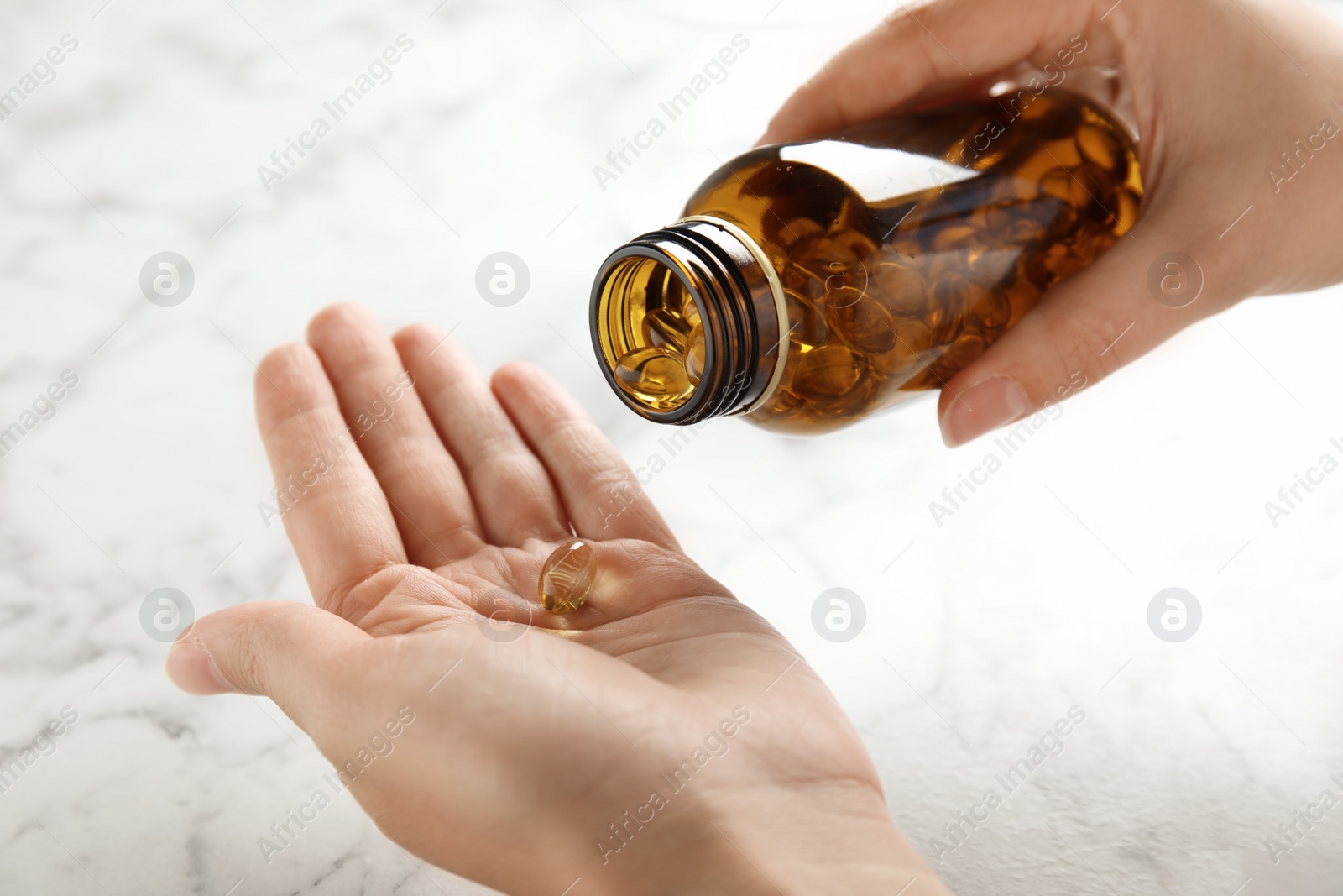 Photo of Woman with fish oil pills at table, closeup