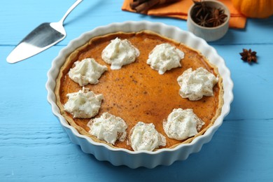 Delicious pumpkin pie with whipped cream on light blue wooden table