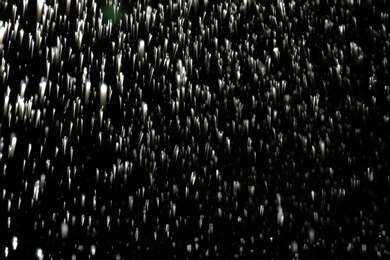 Photo of Rain falling down on dark background. Cold weather