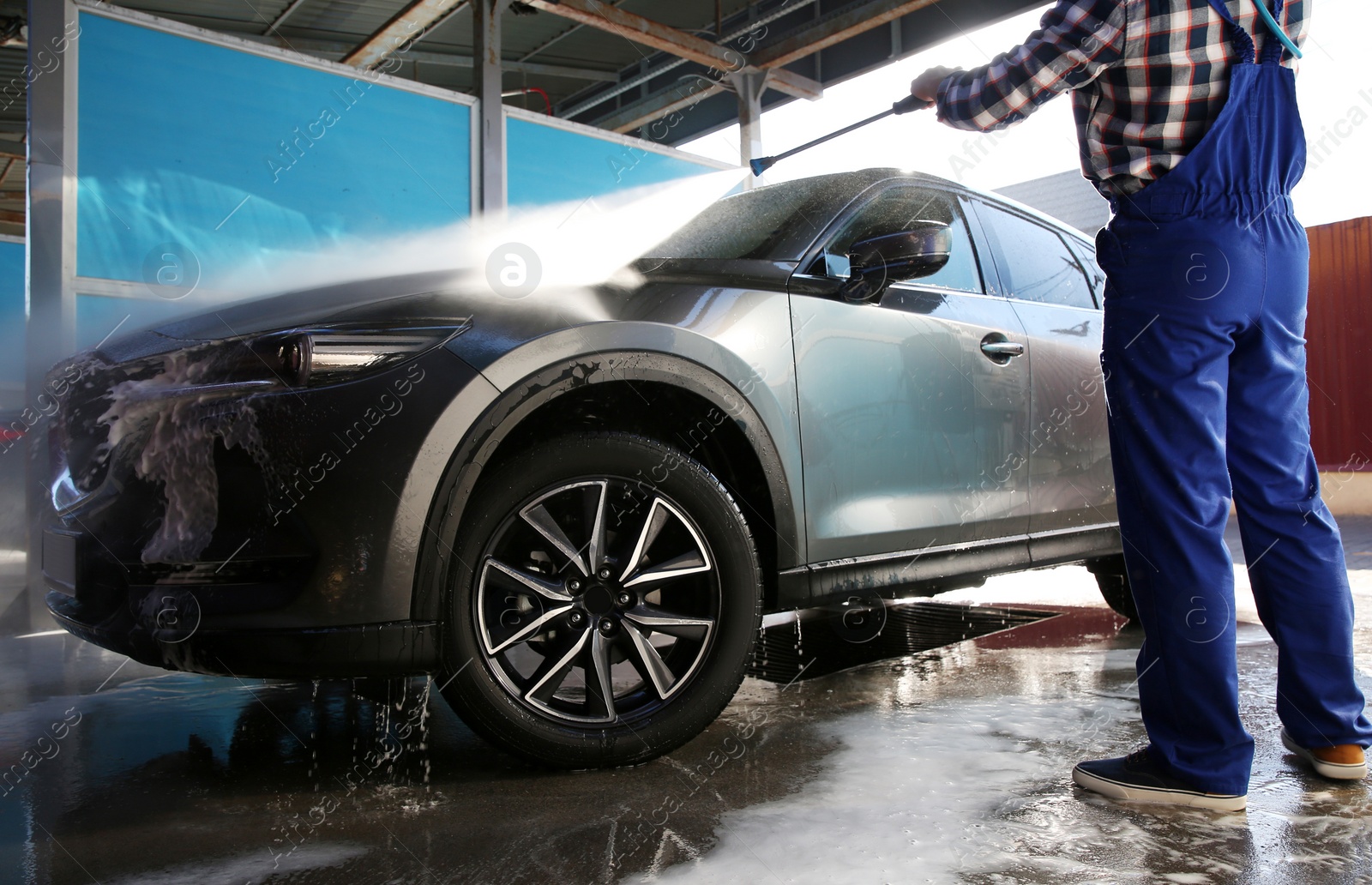 Photo of Worker cleaning automobile with high pressure water jet at car wash