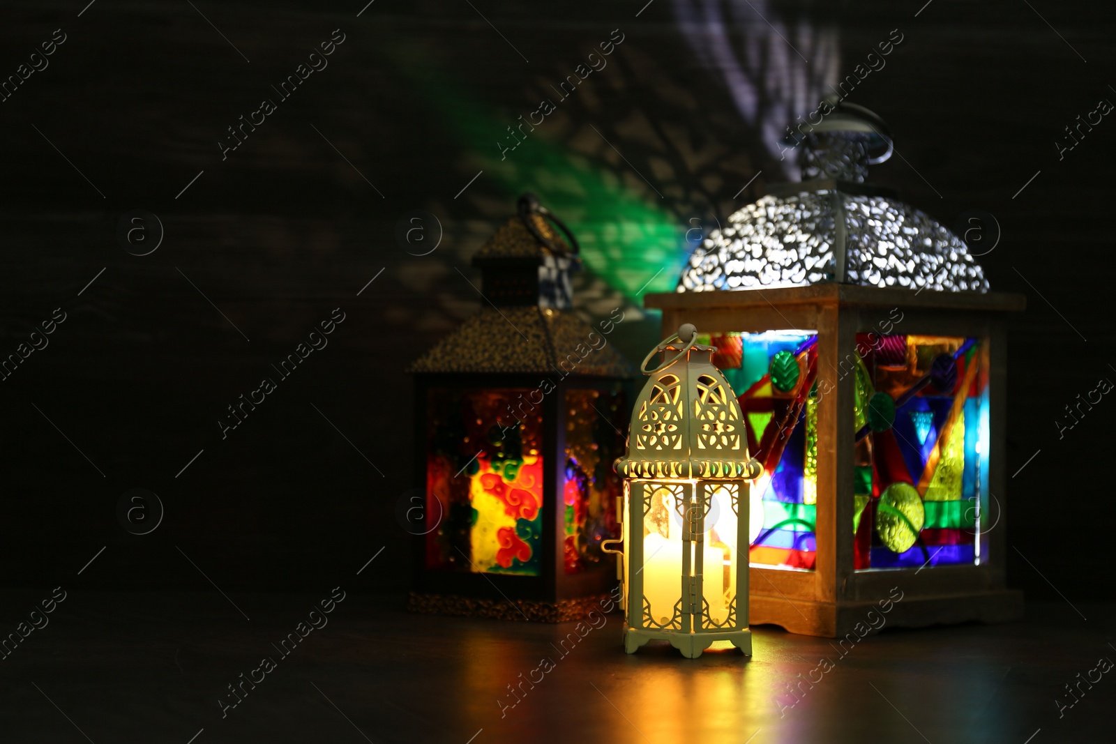 Photo of Decorative Arabic lanterns on table against dark background. Space for text