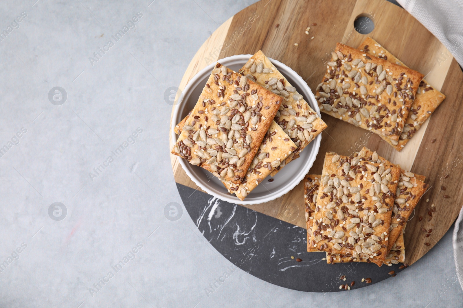 Photo of Cereal crackers with flax, sunflower and sesame seeds on grey table, top view. Space for text