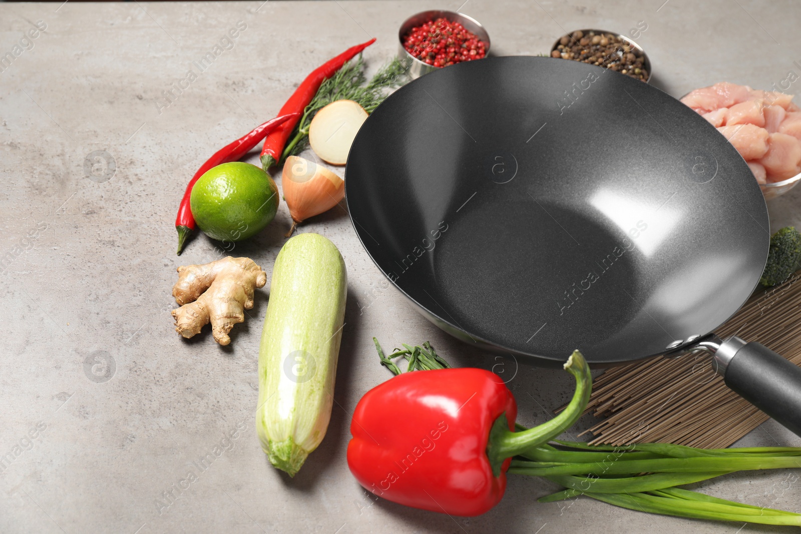 Photo of Empty iron wok and raw ingredients on grey table