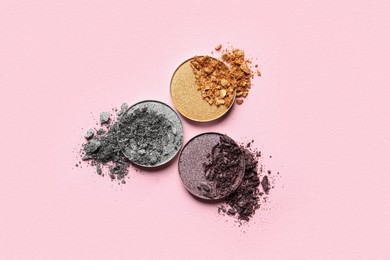 Photo of Different crushed eye shadows on pink background, flat lay