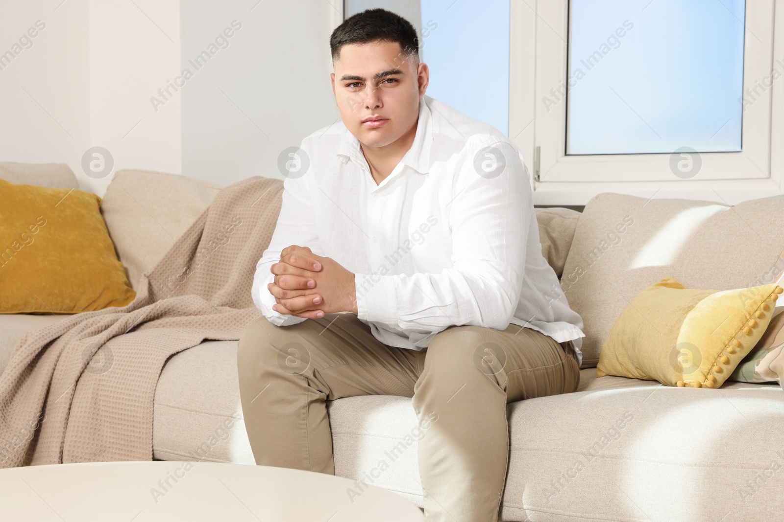 Photo of Attractive groom on sofa indoors. Wedding preparation