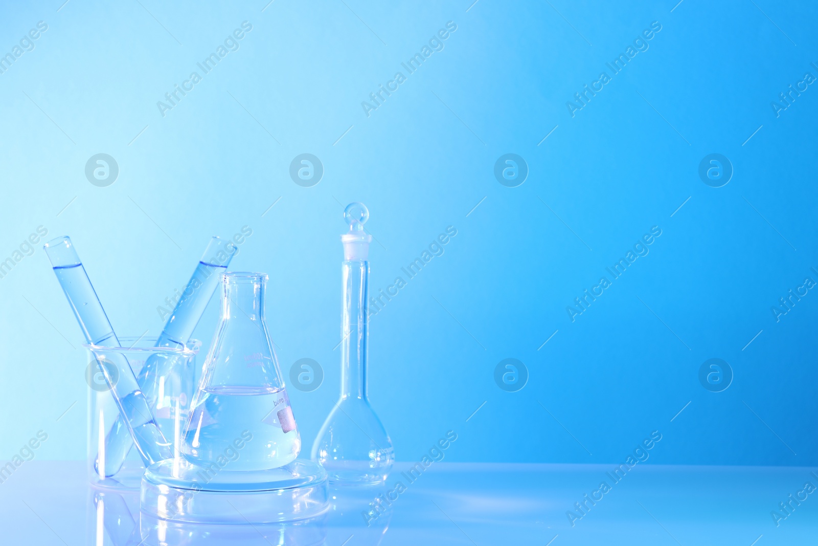 Photo of Laboratory analysis. Different glassware on table against light blue background