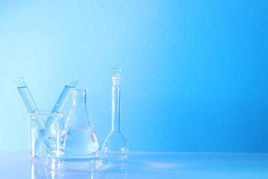 Photo of Laboratory analysis. Different glassware on table against light blue background