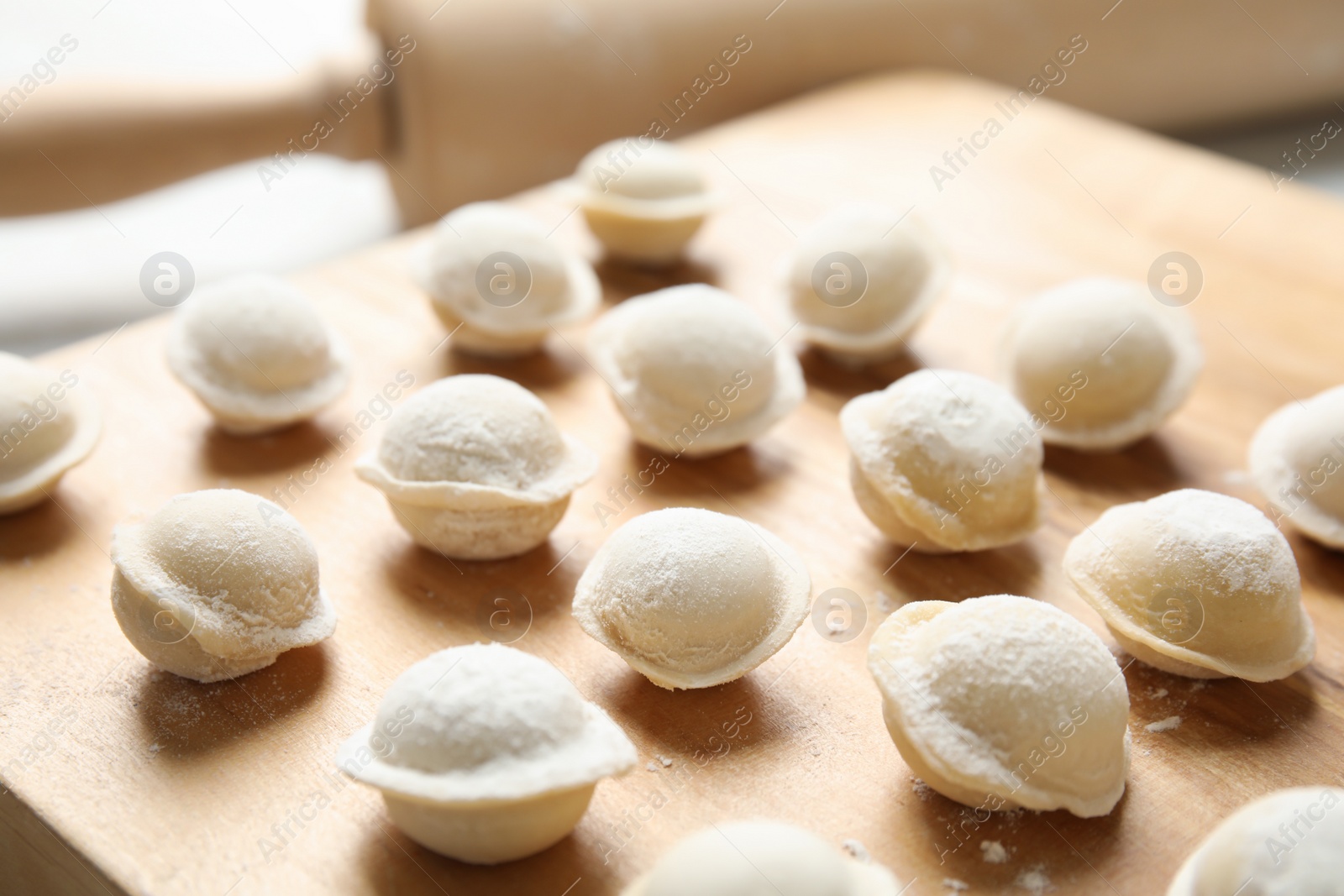 Photo of Board with raw dumplings on table, closeup