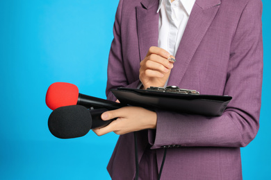 Professional journalist taking notes on light blue background, closeup