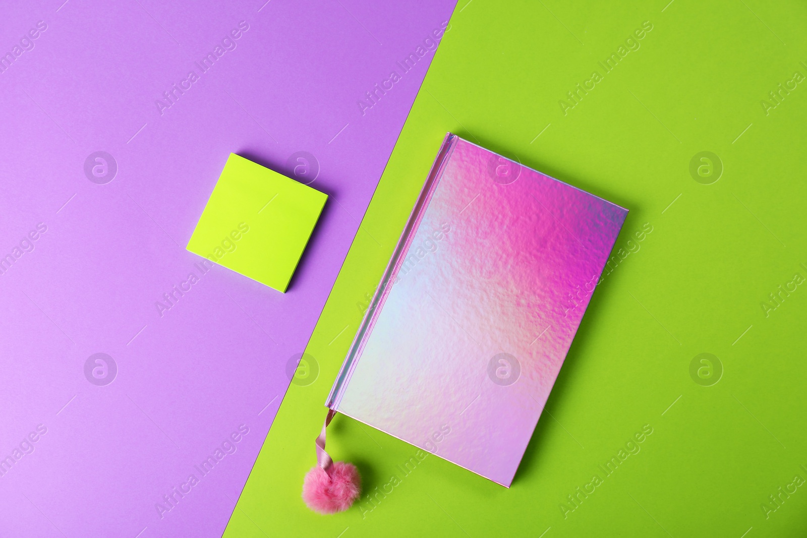 Photo of Pink female notebook with pompom and note papers on color background, flat lay