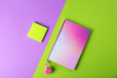 Photo of Pink female notebook with pompom and note papers on color background, flat lay