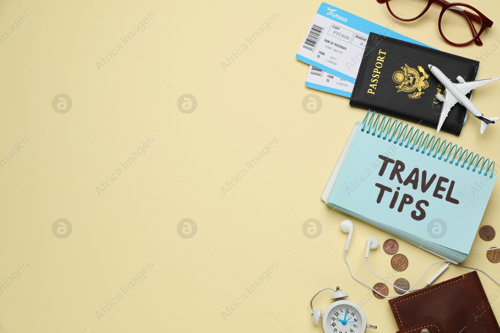 Photo of Notebook with phrase Travel Tips and tourist items on yellow background, flat lay. Space for text