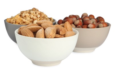 Photo of Ceramic bowls with granola, almonds and hazelnuts on white background. Cooking utensil