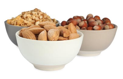 Ceramic bowls with granola, almonds and hazelnuts on white background. Cooking utensil