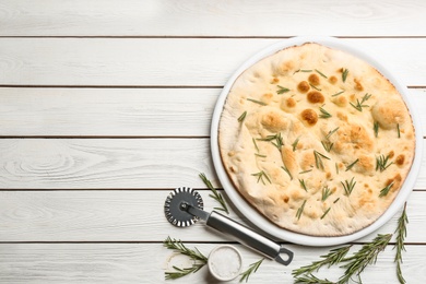 Flat lay composition with focaccia bread on white wooden table. Space for text