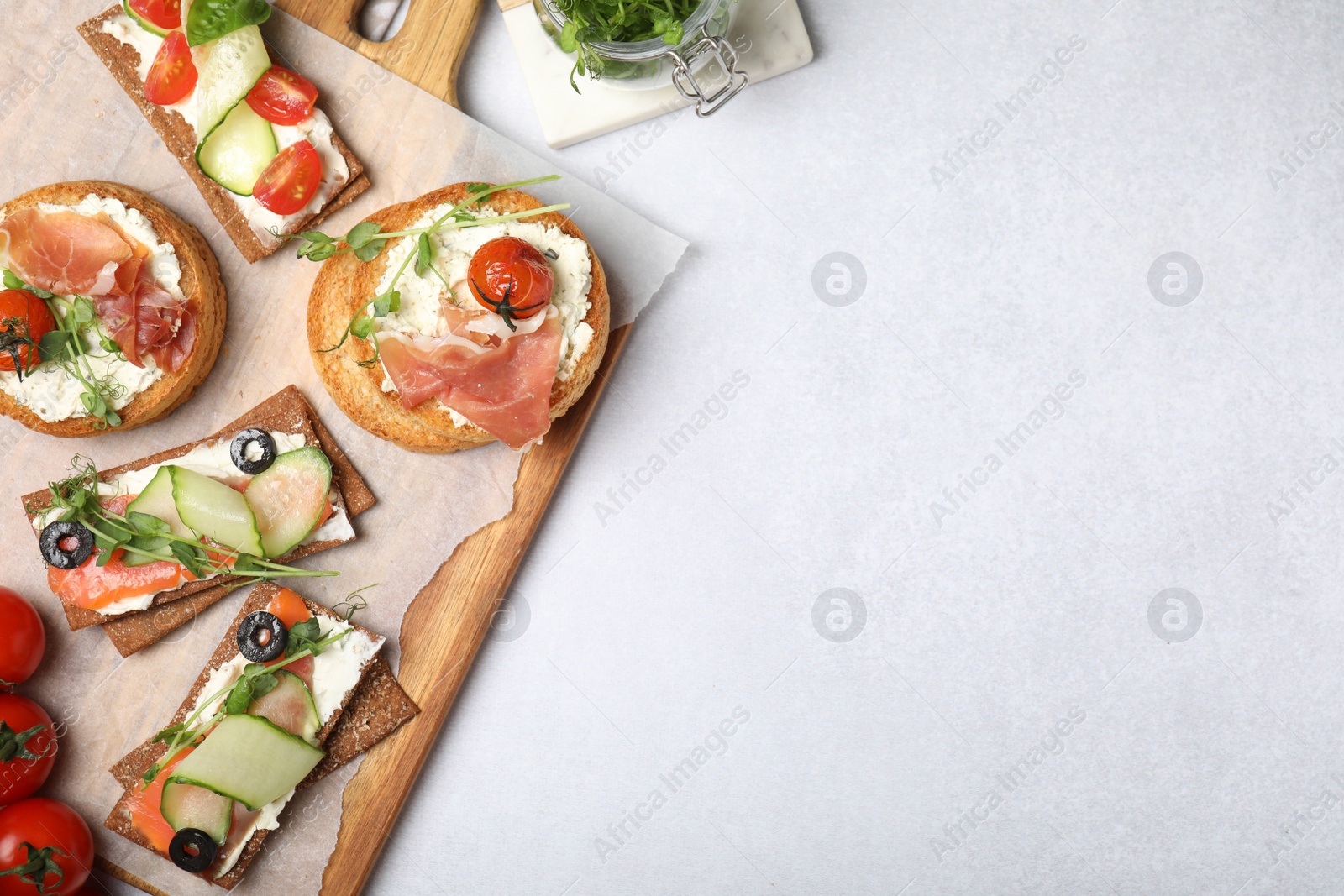 Photo of Tasty rusks and rye crispbreads with different toppings on light grey table, flat lay. Space for text