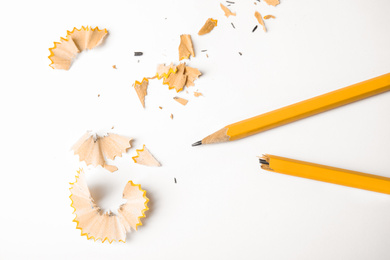 Photo of Broken pencil and shavings on white background, top view