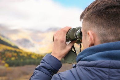 Photo of Boy looking through binoculars in beautiful mountains, closeup. Space for text